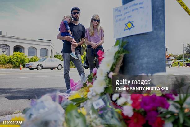 Mourners Troy and Katie McKinney and their son Wynn look over a make-shift memorial across the street from the Chabad of Poway Synagogue on Sunday,...