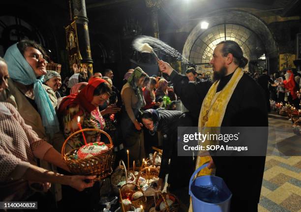 An Orthodox priest seen blessing the traditional Easter cakes and painted eggs prepared for Easter celebrations at the Pechersk Lavra church Orthodox...