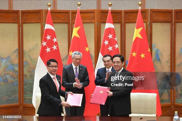 Singapore's Prime Minister Lee Hsien Loong, back left, claps hands with Chinese Premier Li Keqiang, back right, as they attend a signing ceremony on...