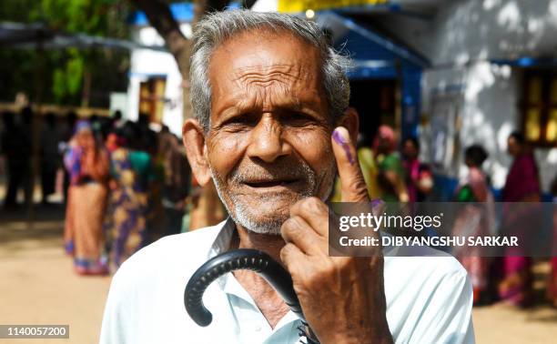 An Indian tribal voter poses for photographs showing his inked finger after casting his vote at a polling station in Illambazar area of the eastern...