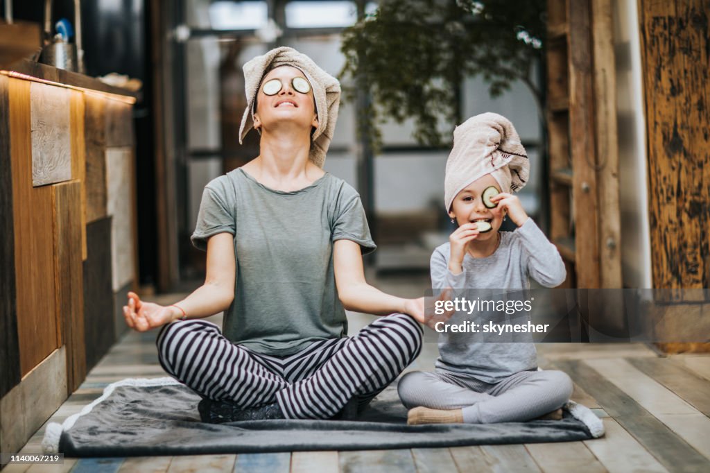 Entspannte Mutter und Tochter trainieren morgens zu Hause Yoga.
