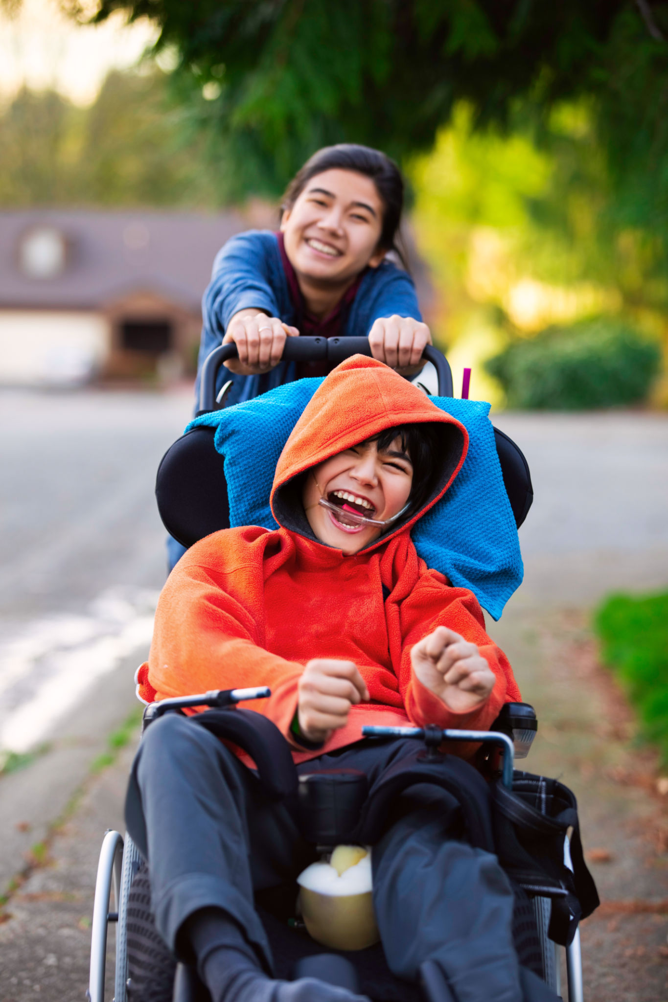 Sister pushing disabled little brother in wheelchair around neighborhood Sister pushing disabled little brother in wheelchair around neighborhood