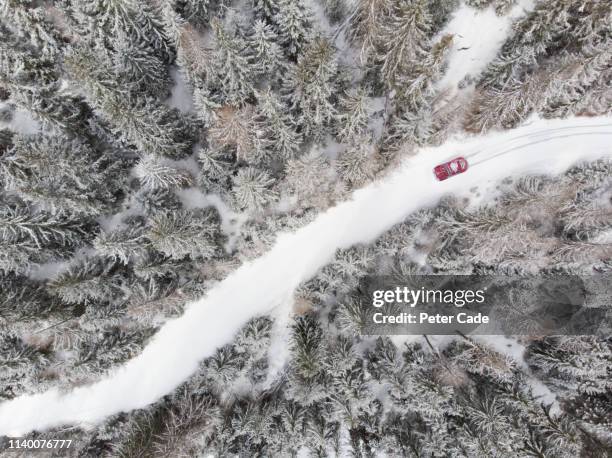 car on snowy road through forest - reifenspur stock-fotos und bilder