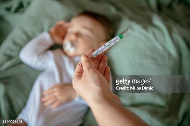 krankes baby mit hohem fieber - grippevirus stock-fotos und bilder