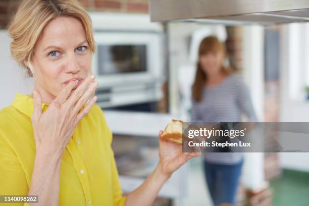 women eating cake in kitchen - women licking women stock-fotos und bilder