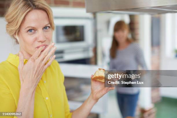 women eating cake in kitchen - finger in mouth fotografías e imágenes de stock