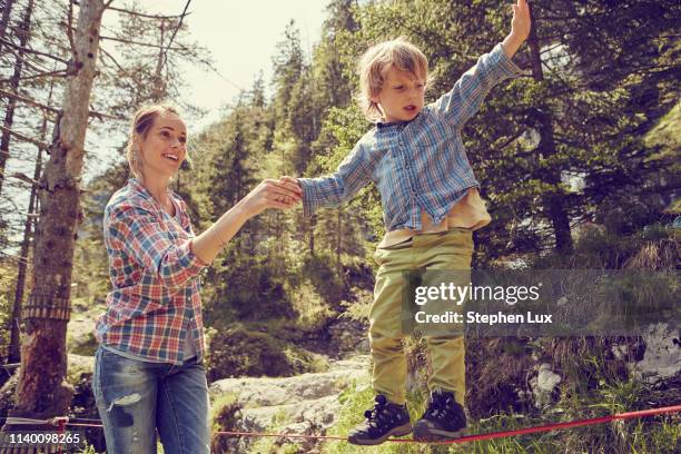 boy balancing on rope with help from mother, ehrwald, tyrol, austria - slackline stockfoto's en -beelden