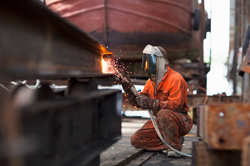 Welder welding girder in shipyard workshop