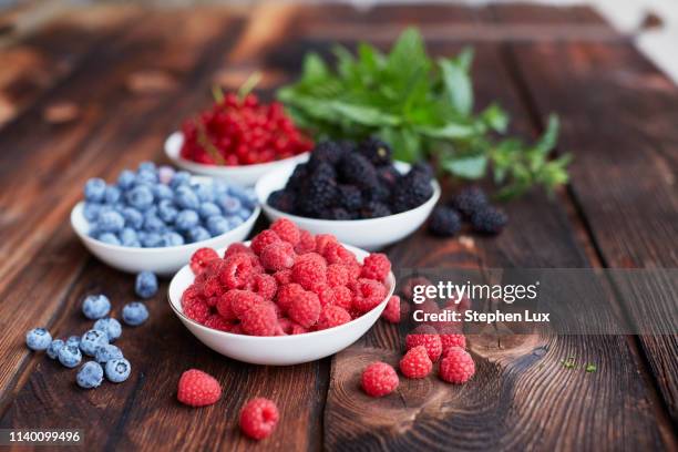 picnic table with four bowls of fresh berries - berry fruit stock-fotos und bilder