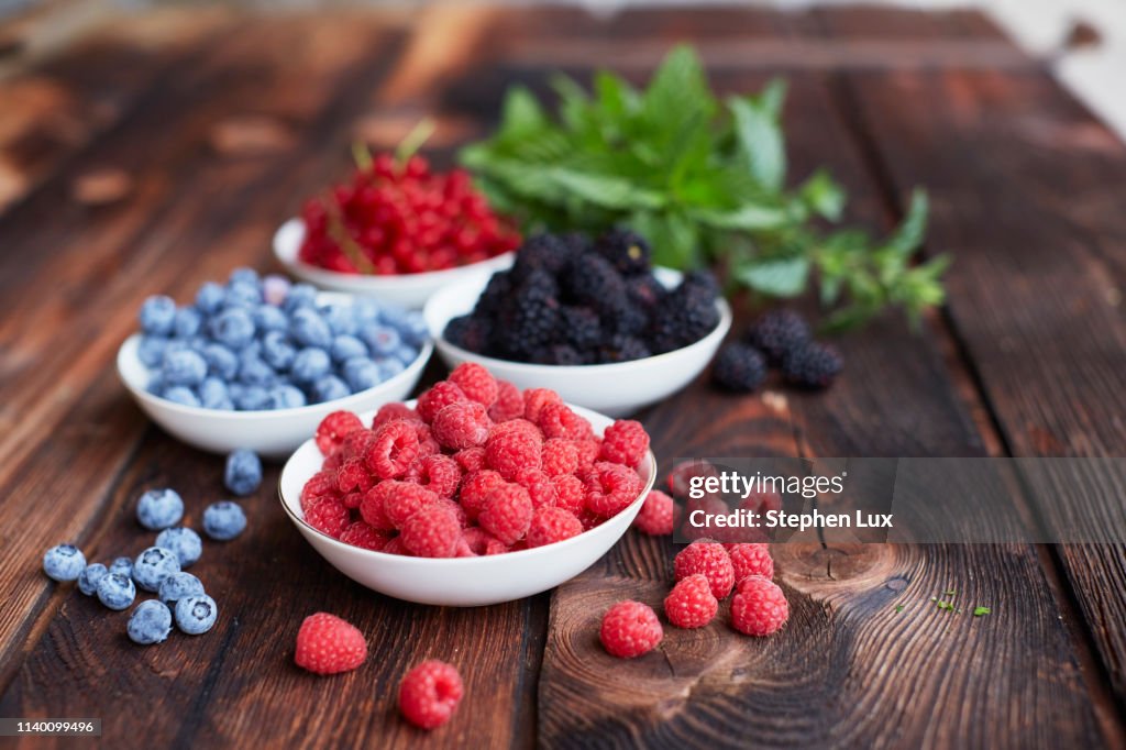 Picnic table with four bowls of fresh berries