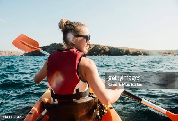 rear view of mid adult woman sea kayaking, menorca, balearic islands, spain - kayaking stock pictures, royalty-free photos & images