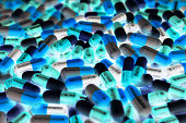 Pile of blue, green, and white color of capsule pills with modern design light. Toxicology medicine concept. QC and QA in pharmaceutical industry background. Global healthcare.