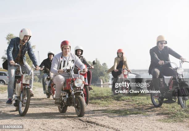 group of friends riding mopeds beside lake - mobylette photos et images de collection