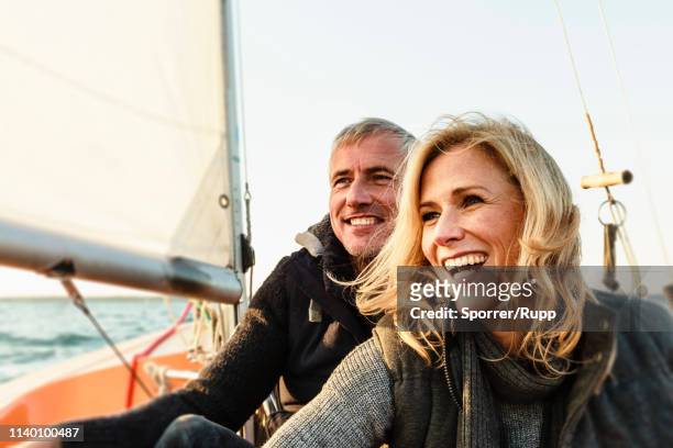 mature couple on sailing boat, smiling - segeln stock-fotos und bilder