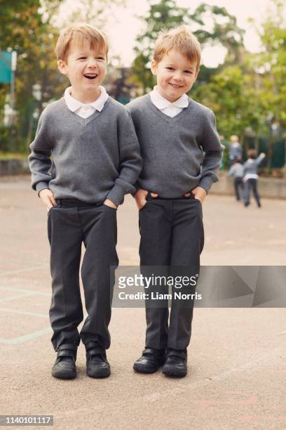 portrait of elementary schoolboy twins in playground - boy school uniform stock-fotos und bilder