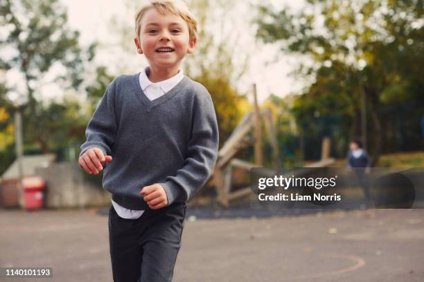 portrait of elementary schoolboy running in playground - britain playgrounds fotografías e imágenes de stock