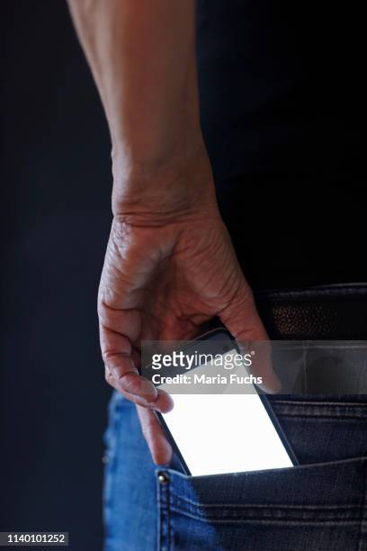 womans hand removing smartphone from back pocket - back pocket photos et images de collection