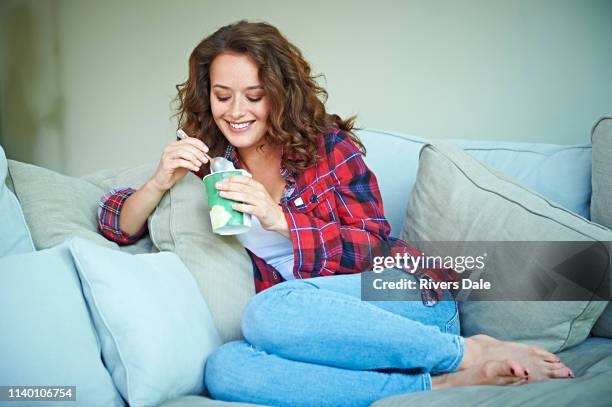 woman eating ice-cream on sofa - woman ice cream stock pictures, royalty-free photos & images