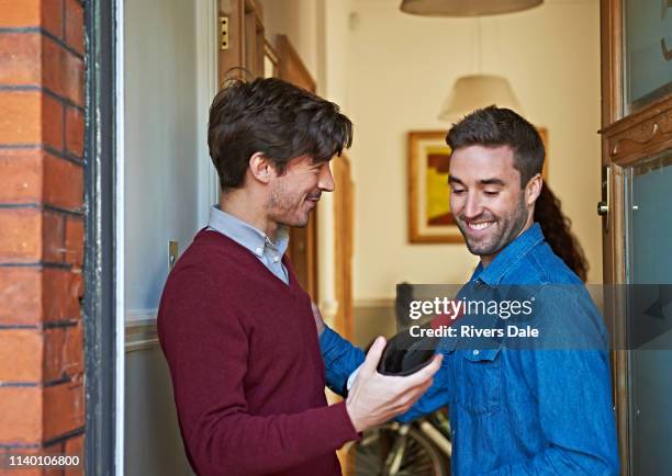 men with bottle of wine smiling at front door - vinger bildbanksfoton och bilder