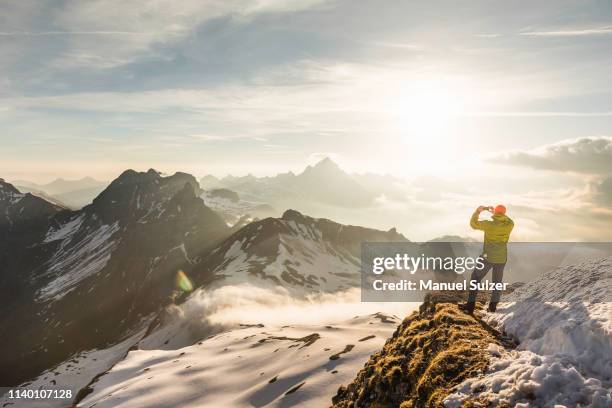 young male mountain trekker photographing view of clouds, bavarian alps, oberstdorf, bavaria, germany - oberstdorf stock-fotos und bilder