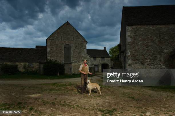 portrait of mature traditional farmer and his lurcher dog in farmyard - lurcher fotografías e imágenes de stock