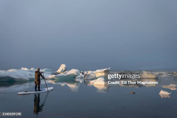 man on paddleboard, jokulsarlon glacier lagoon, skaftafell national park, iceland - jökulsárlón lagoon stock-fotos und bilder