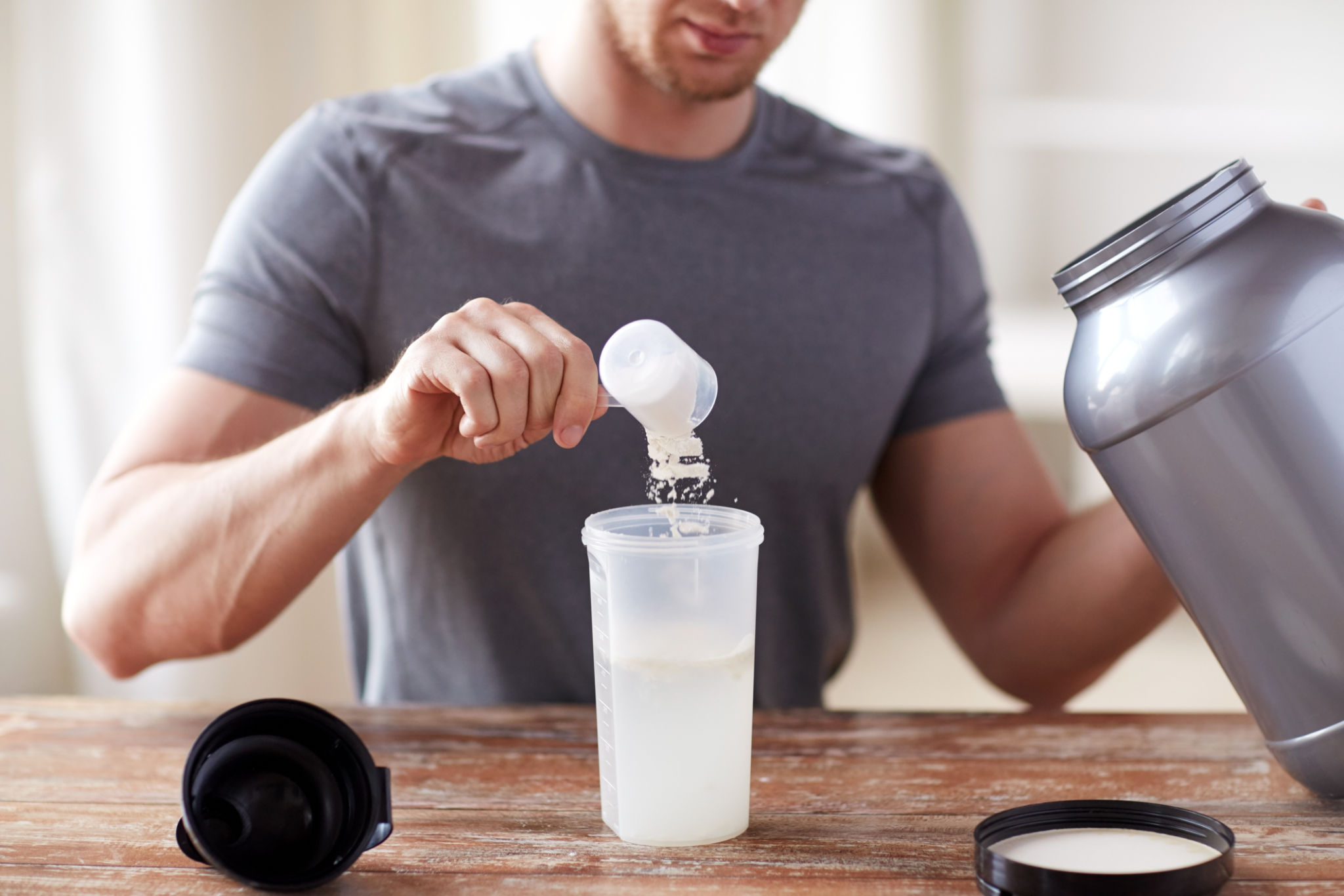 Feche acima do homem com frasco e frasco da agitação da proteína Feche acima do homem com frasco e frasco da agitação da proteína