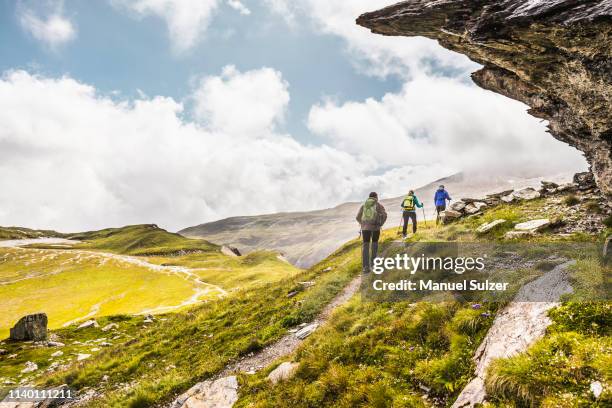 rear view of three hikers hiking beneath rock overhang, fil de cassons, segnesboden, graubunden, switzerland - hiker stock-fotos und bilder