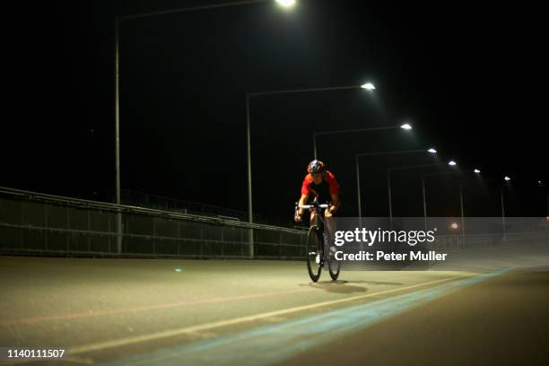 cyclist cycling on track at velodrome, outdoors - fahrrad nacht stock-fotos und bilder