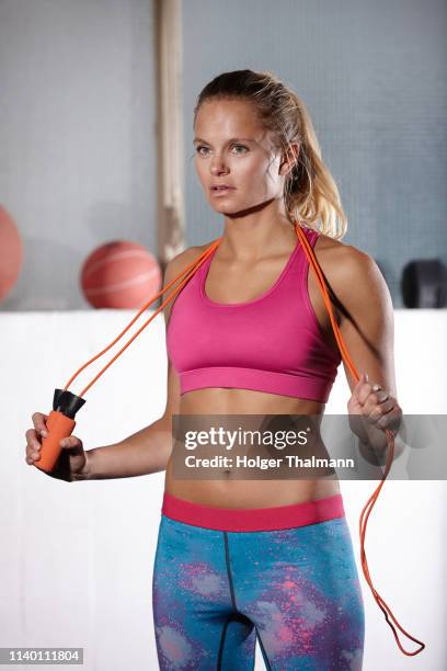 portrait of young woman with skipping rope on shoulders in gym - bauchfreies oberteil stock-fotos und bilder