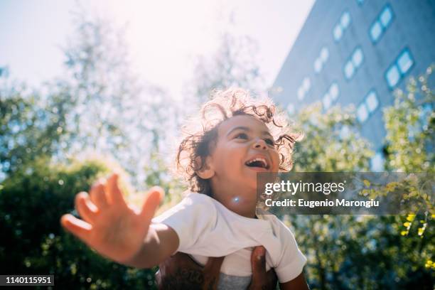 father swinging son up in air in park - in the park day 2 stock pictures, royalty-free photos & images