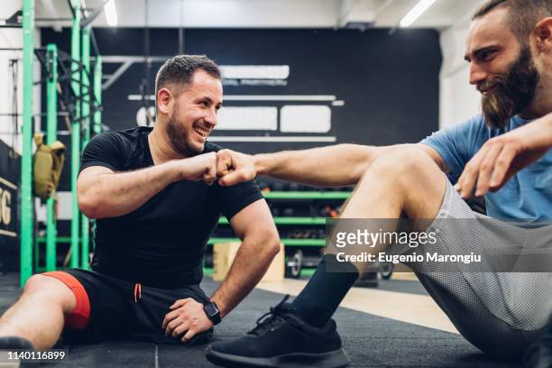 Personal trainer and man with disability enjoying conversation in gym