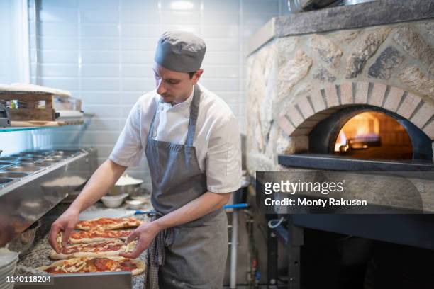 chef putting tomato sauce onto pinsa romana, a roman style pizza blend reducing sugar and saturated fat, containing rice and soy with less gluten - pizzaugn bildbanksfoton och bilder