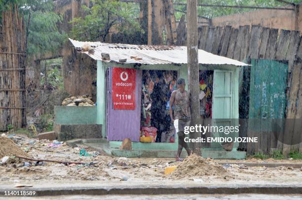 Man stands under the pouring rain in front of his shop in the Paquite district of Pemba on April 29 as Cyclone Kenneth hit northern Mozambique,...