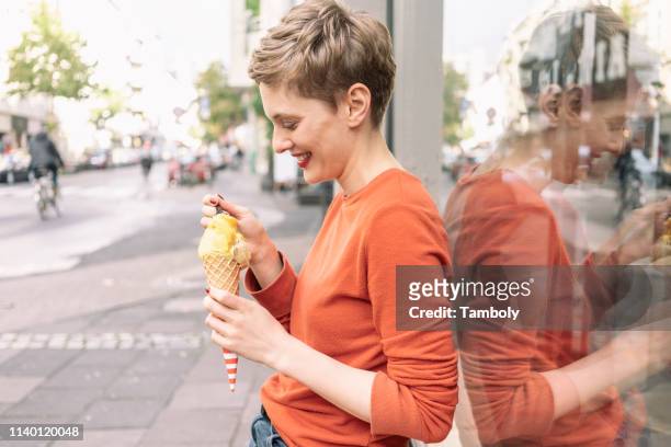 woman eating ice cream in front of shop, cologne, nordrhein-westfalen, germany - sweet shop stock-fotos und bilder