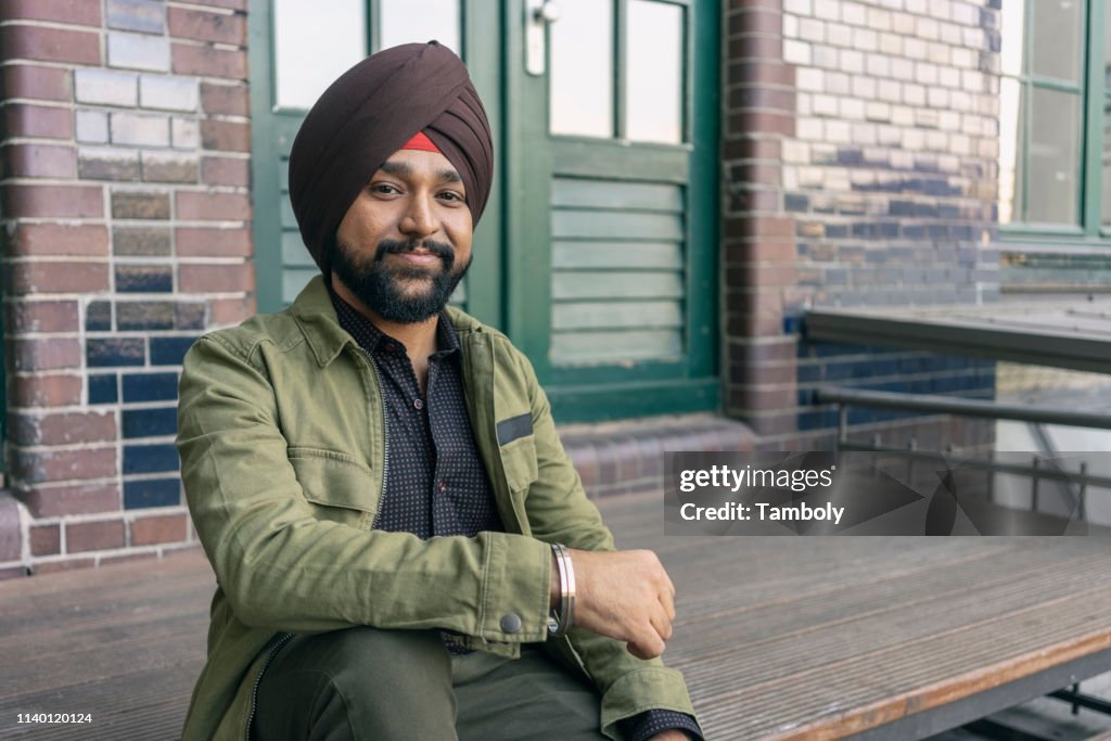 Indian man in front of building with brickwall, Berlin, Germany