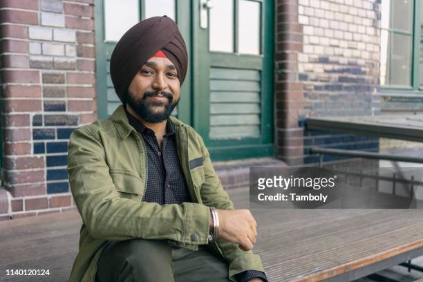 indian man in front of building with brickwall, berlin, germany - sikh foto e immagini stock
