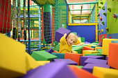 Cute little boy plays with soft cubes in the dry pool in play center. Kid playing on indoor playground in foam rubber pit in trampoline.