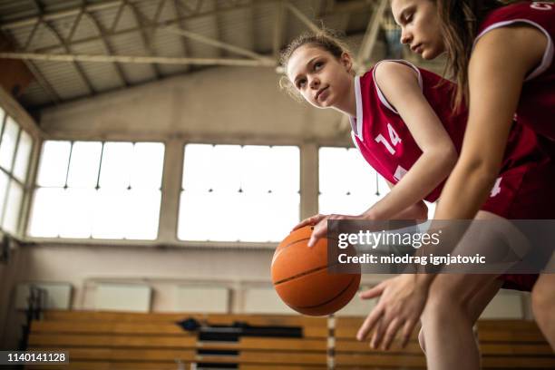mädchen verteidigt ball vom gegner während des spiels - basketball teenager stock-fotos und bilder