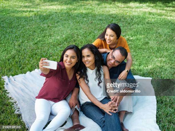una mujer joven tomando una selfie con su familia - mexican picnic fotografías e imágenes de stock