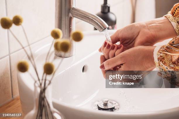 frau reinigt hände im waschbecken des badezimmers - bathroom sink stock-fotos und bilder