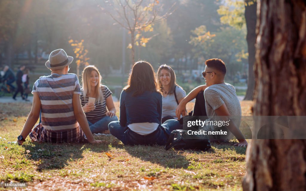 Groep van vijf vrienden lachen hardop buiten, het delen van goede en positieve stemming