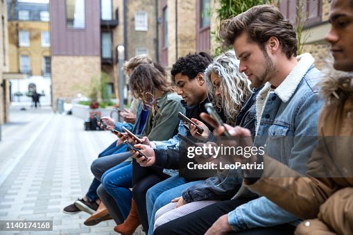 Group of teenage friend focused on their own smartphone texting on social media Group of teenage friend focused on their own smartphone texting on social media