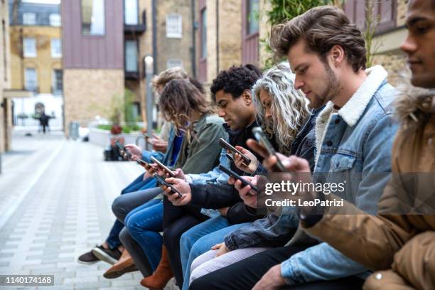 group of teenage friend focused on their own smartphone texting on social media - friends loneliness imagens e fotografias de stock