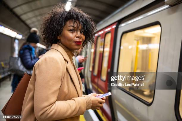 mujer esperando el tren del metro - transporte público fotografías e imágenes de stock