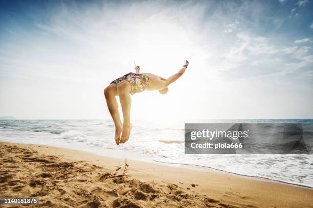 man flips and spins a sommersault on the beach - backflipping stock pictures, royalty-free photos & images