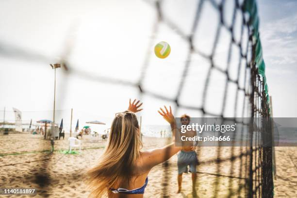 gli amici giocano a beach volley e si divertono - beach volley foto e immagini stock