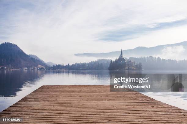 slovenia, gorenjska, bled, bled lake, jetty with view to bled island with church of mary's assumption - lakeshore 個照片及圖片檔