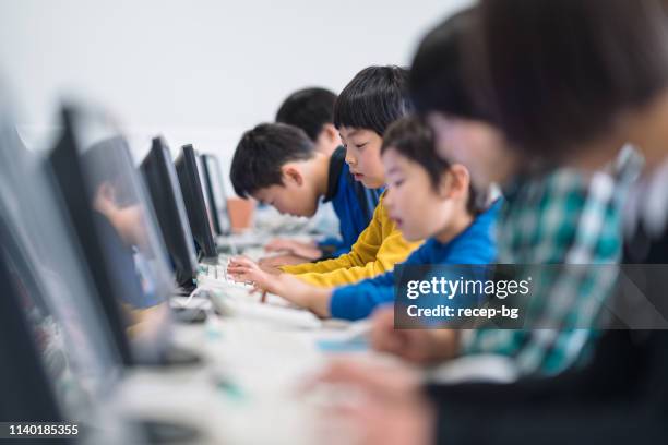 group of elementary school children learning to use computer at school - computer training stock pictures, royalty-free photos & images