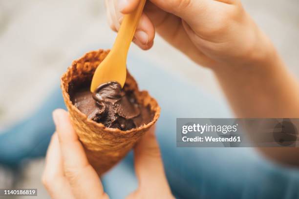 woman's hand holding ice cream cone with cholocolate ice, close-up - glace au chocolat photos et images de collection